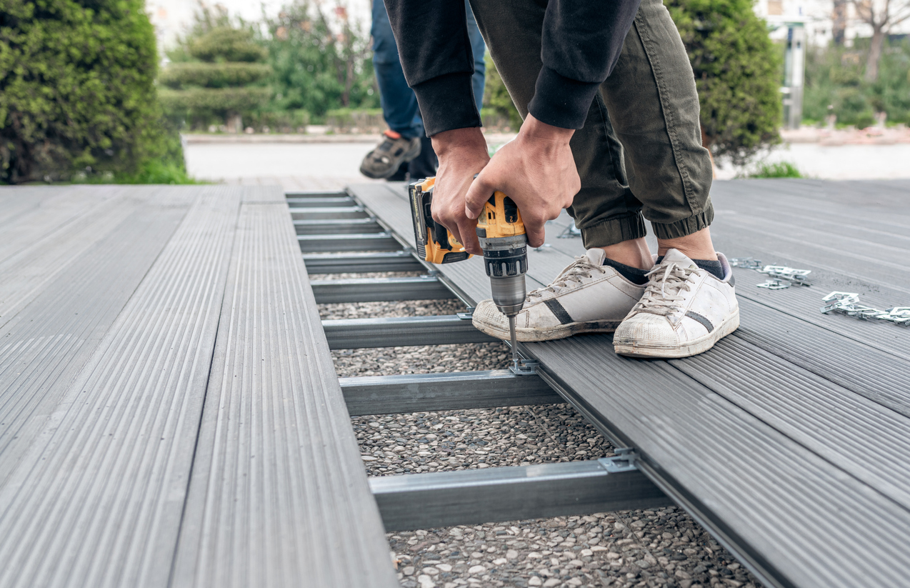 Man assembling composite deck using cordless screwdriver.