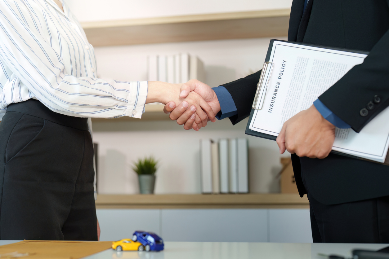 Insurance Agreement. Client and agent shaking hands after signing policy.